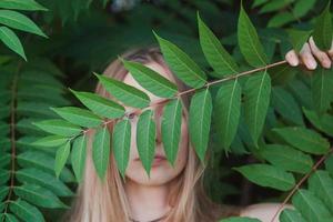 Portrait of beautiful young woman in green leaves, blonde pretty lady in spring bushes photo