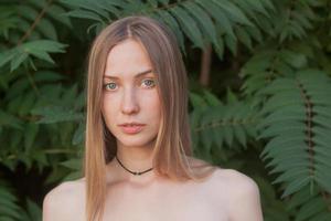 retrato de una bella joven con hojas verdes, una bella dama rubia con arbustos de primavera foto