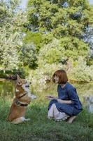 oung woman in retro dress with funny corgi dog on the picnic photo