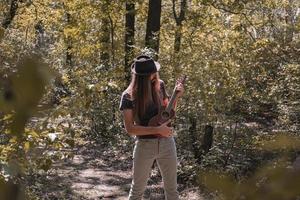 Bearded male with longhait and hat posing with ukulele in the forest photo