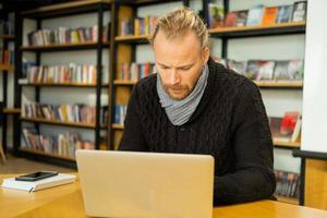 Handsome male read book and work in modern library photo