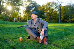 joven hipster masculino lee un libro en el parque de otoño foto