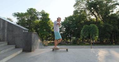 knappe jonge man met skateboard buiten in de stad luister naar muziek met een koptelefoon video