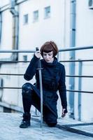 portrait of young redhead woman with japanese sword dressed in futuristic cyberpunk costume standing on the roof. photo