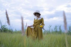 mujer joven pelirroja con pecas en vestido vintage hecho a mano caminar en campos con flores foto