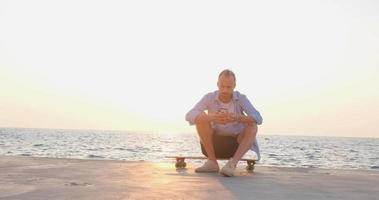 Young handsome male ride on the skateboard , sea and sunset on background video