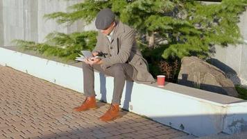 jovem macho ler livro ao ar livre na rua