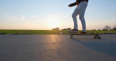 jovem passeio masculino no skate longboard na estrada rural em dia ensolarado video
