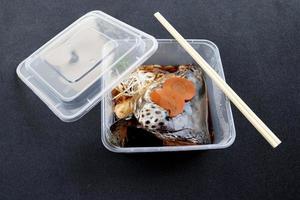 Boiled salmon head with soy sauce, Salmon kabutoni in square plastic box for take home and black background. photo