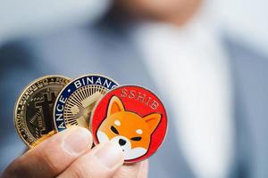 Golden bitcoin coin Shiba coin , Binance Coin BNB group included with Cryptocurrency on hand business man wearing a blue suit. Filed and put and give to me. Close up and Macro photography concept. photo