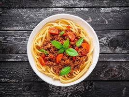 pasta bolognese with tomato sauce, ground minced beef, basil leaves on background photo