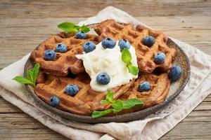 Chocolate banana waffles with blueberries, on dark wooden old table. Side view photo