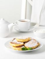 Fried cheese cakes, sweet cheese pancakes on white plate on white background. Home tea party photo