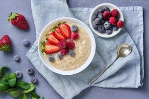 avena con arándanos, fresas, frambuesas sobre fondo azul oscuro foto