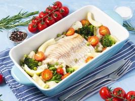 Fish cod baked in blue oven with vegetables - broccoli, tomatoes. Healthy diet food. photo