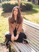 Beautiful teen girl sitting in the Park on a bench, dreaming, thinks. Woman with long hair photo