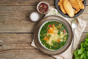 Rustic chicken soup with garnish, parsley, vegetables, homemade dish on old photo