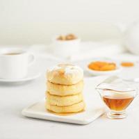 Fried cheese cakes, sweet cheese pancakes on white plate on white background. Home tea party photo