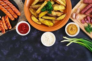 Baked potato wedges with sausages and spices. Top view photo