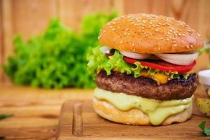 Delicious handmade burger on wooden background. Close view photo