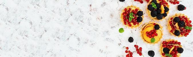 Tartlets with different berries on white background. Top view. Banner. photo