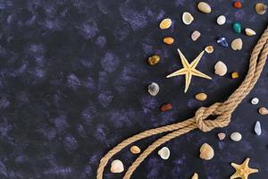 Seashell, starfish and rope on dark background. Top view photo