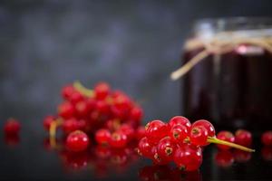 Jar with jam of red currant on dark background photo