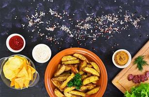 Baked potato wedges with sausages and spices. Top view photo