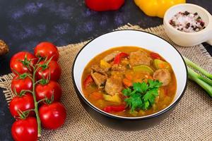 estofado con carne y verduras en salsa de tomate sobre fondo oscuro foto