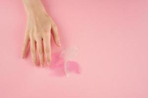 Woman touching pink leaves on pastel background top view copy space, concept photo