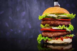 Delicious handmade burger on dark background. Close view photo