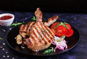 Raw pork steak with herbs on dark background. Raw juicy steak on bone