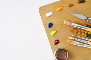 palette with paints and brushes for oil painting on a white background photo