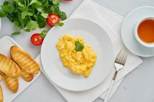 Scrambled eggs, Omelette. Breakfast with pan-fried eggs, cup of tea photo