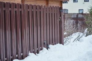 Metal Fence and snow in countryside, gate with padlock, side view photo