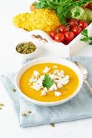 Pumpkin cream soup with feta cheese, autumn homemade food, white background, vertical closeup photo