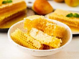honey in honeycomb, close-up, on white ceramic plate, on wooden rustic table, side view, sunlight photo