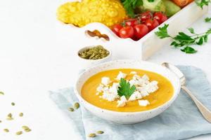 Pumpkin cream soup with feta cheese, autumn homemade food, white background, closeup, copy space photo