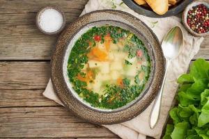 Rustic chicken soup with garnish, parsley, vegetables, homemade dish on old dark table, top view photo