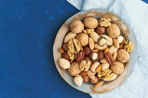 azul clásico en la comida. mezcla de nueces en el plato - nuez, almendras, pecanas, macadamia foto