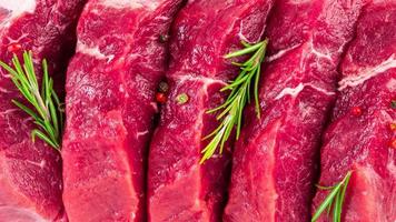 background of fresh raw sliced beef steaks, garlic, rosemary and seasonings. Juicy meat banner photo