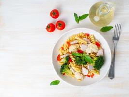 Pasta fusilli with vegetables, turkey meat on white wooden table, low-calorie diet, low-fat food, top view, copy space