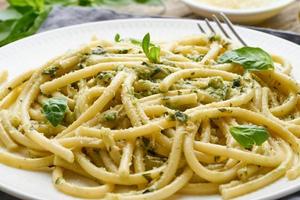 Pesto spaghetti pasta with basil, garlic, pine nuts, olive oil. Rustic table, macro photo
