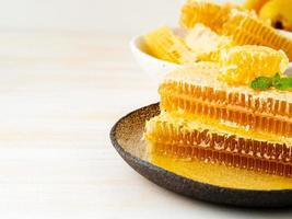 honey in honeycomb, close-up, on brown ceramic plate, on wooden white rustic table, copy space photo