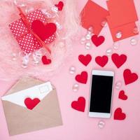 regalo en caja de regalo roja con lazo, teléfono inteligente, sobre, tarjeta, corazón rojo, fondo rosa, vista superior, espacio de copia