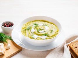 large white bowl with vegetable green cream soup of broccoli, zucchini, green peas photo