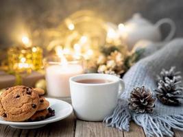 Cozy evening, cup of drink, Christmas decorations, candles and lights garlands photo