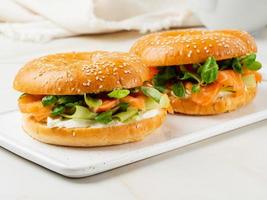 Two sandwiches with salmon, cream cheese, cucumber slices on white marble table photo