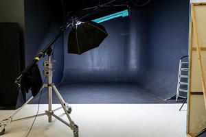 Empty photo studio with lighting equipment. Photographer workplace interior with professional tool set gear. Flash light black background scenes ready for studio shooting. Modern photographer studio