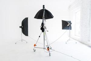 Empty photo studio with lighting equipment. Photographer workplace interior with professional tool set gear. Flash light white background scenes ready for studio shooting. Modern photographer studio